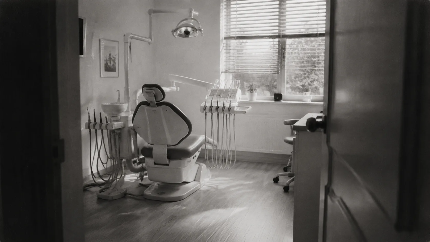 Illustrative dental treatment room with daylight through blinds.